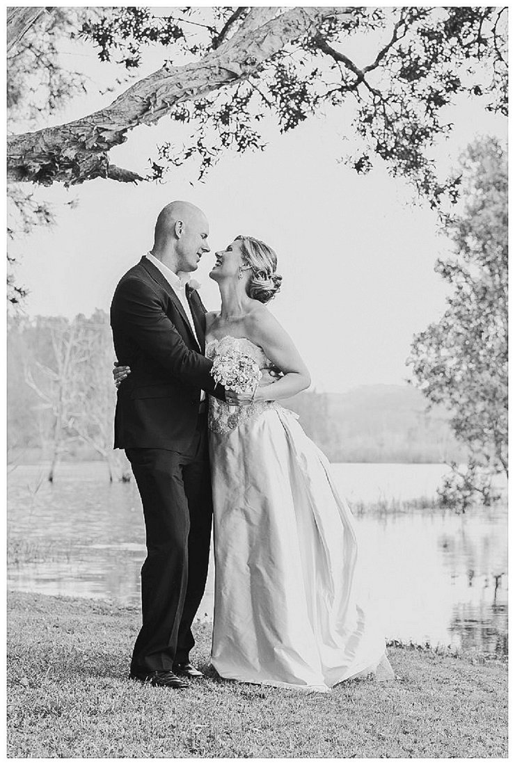 black and white photo of bride and groom near a lake
