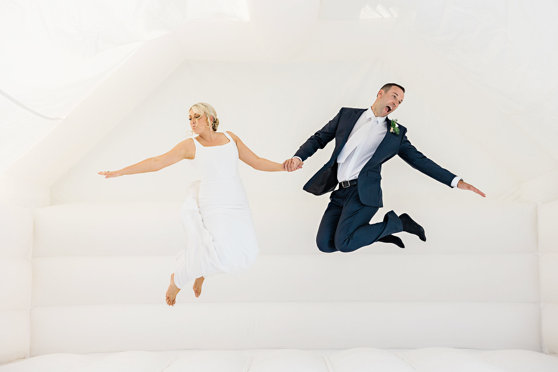 bride and groom jumping on a white jumping castle