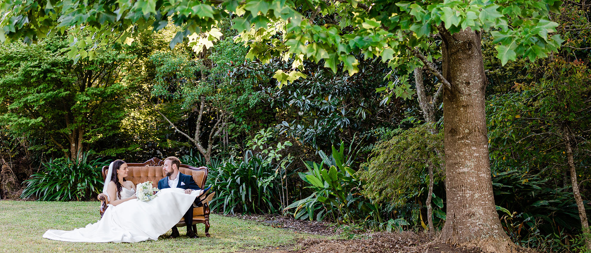 bride and groom on a seat under a tree