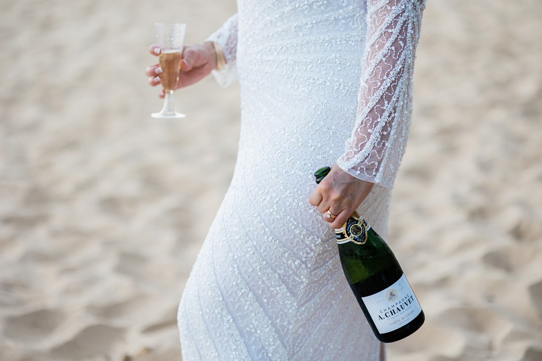 bride at the beach with a bottle of champagne